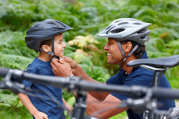 Visuel d'un petit garçon et son papa en train de lui attacher son casque de vélo