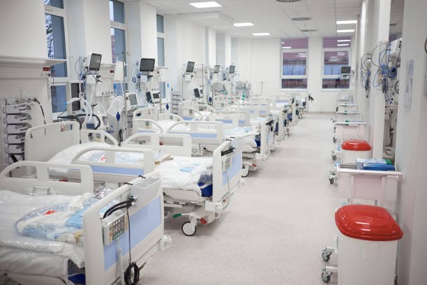 Visuel d'une salle remplie de lits d'hôpital vides alignés évoquant une salle de réveil